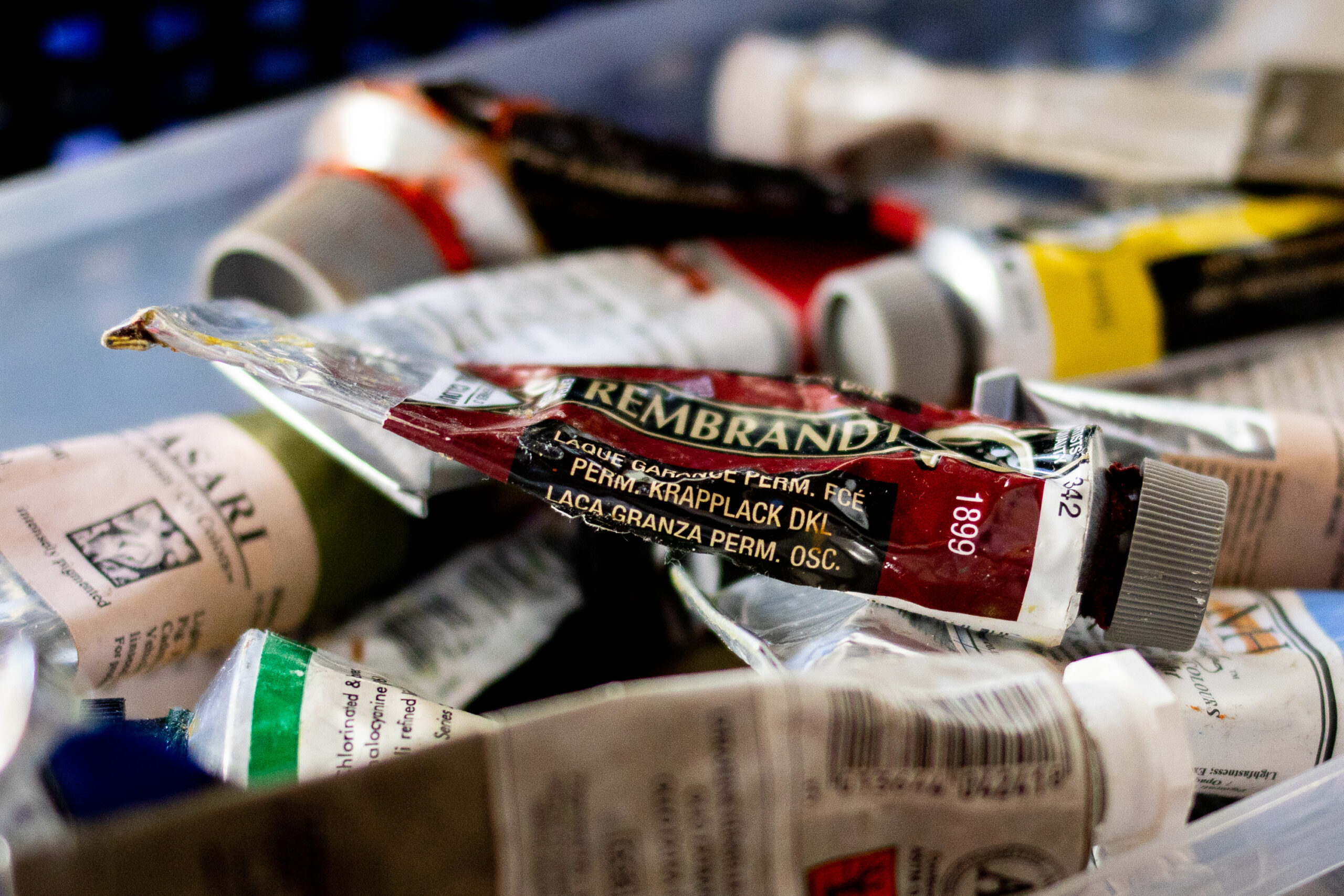A mess of paint tubes sits within a clear container.