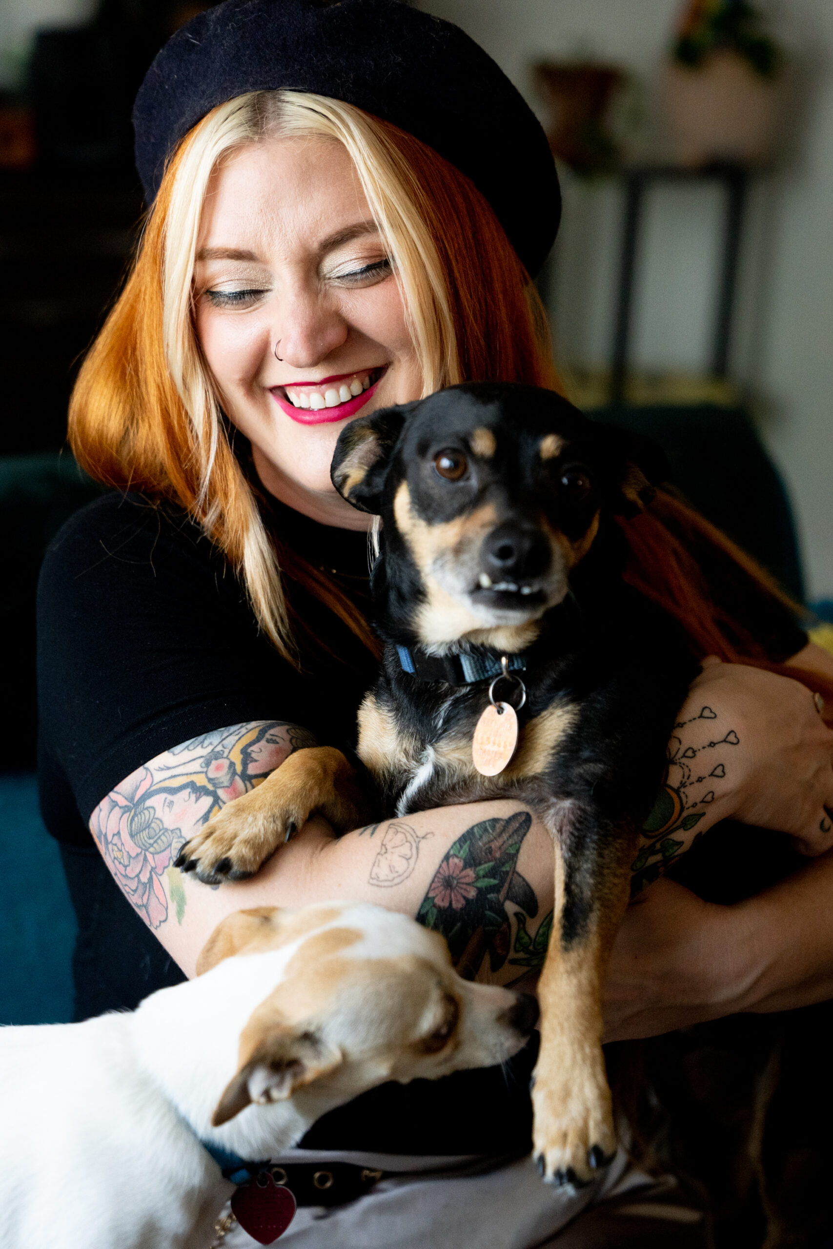A closeup of a white woman smiles holding her two small dogs.